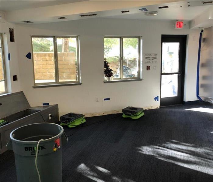 Air movers in a room with removed baseboards and ventilation holes cut into walls and ceiling