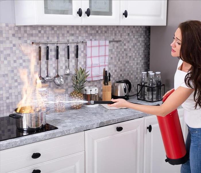 lady using a fire extinguisher in the kitchen